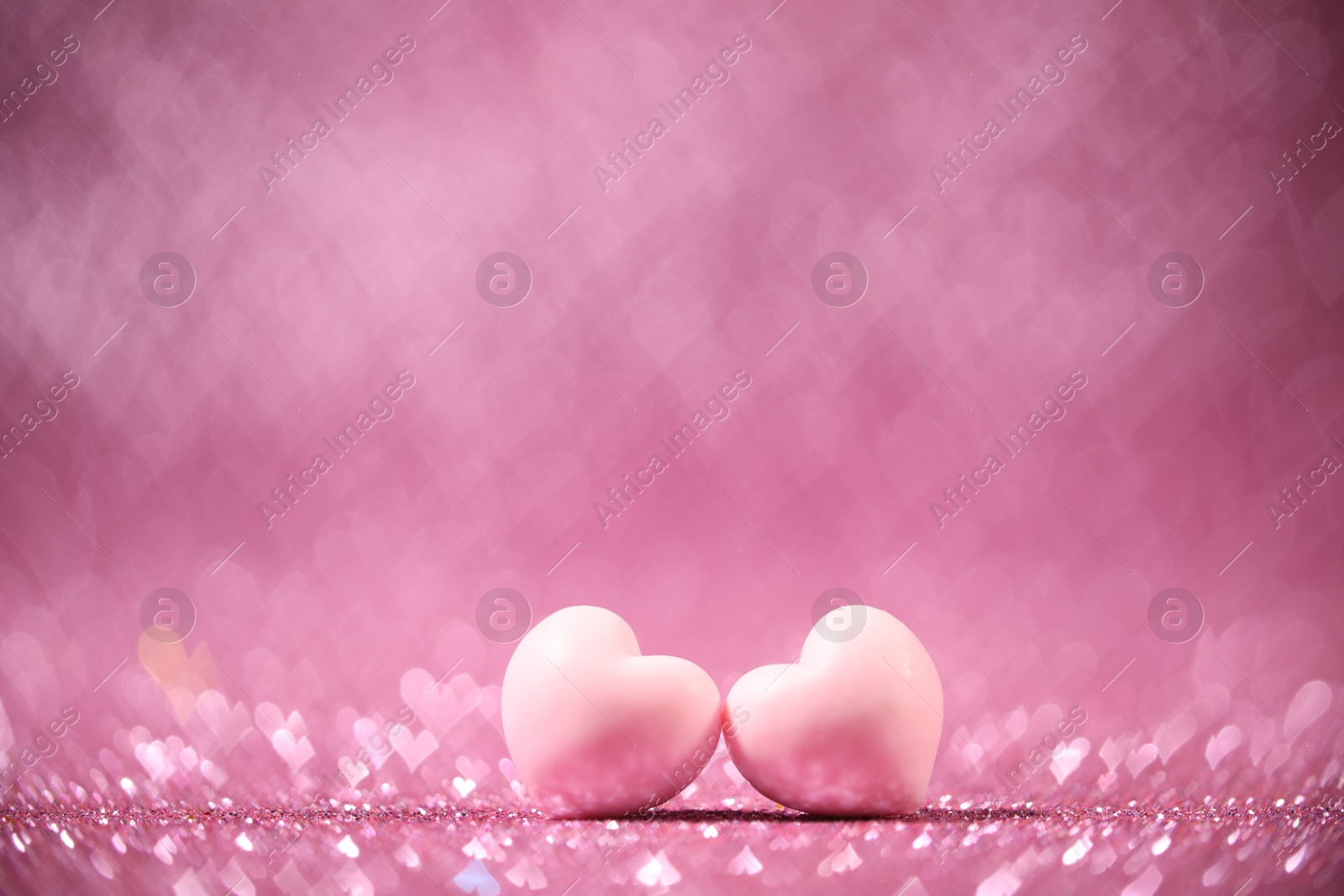 Photo of Romantic decor. Small hearts on shiny pink glitter and heart shaped lights, space for text. Bokeh effect