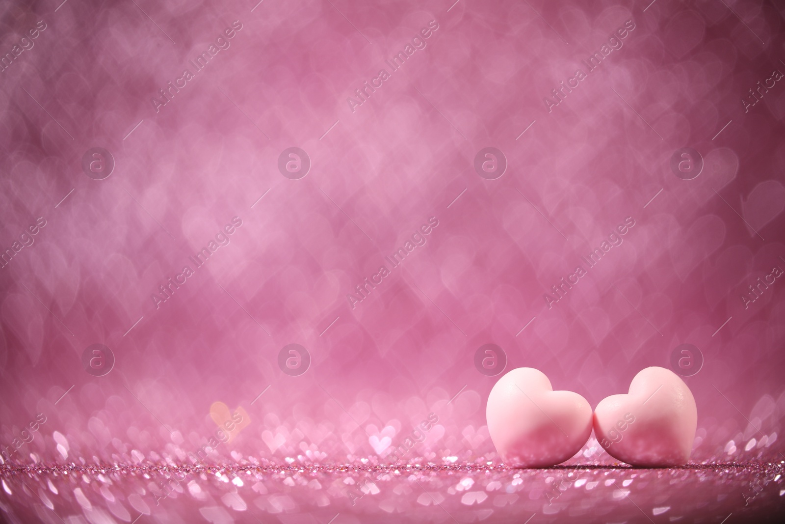 Photo of Romantic decor. Small hearts on shiny pink glitter and heart shaped lights, space for text. Bokeh effect