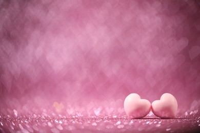 Photo of Romantic decor. Small hearts on shiny pink glitter and heart shaped lights, space for text. Bokeh effect