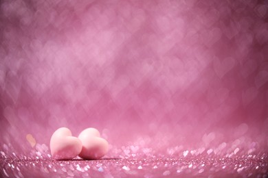 Photo of Romantic decor. Small hearts on shiny pink glitter and heart shaped lights, space for text. Bokeh effect