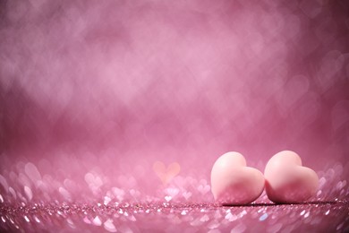 Photo of Romantic decor. Small hearts on shiny pink glitter and heart shaped lights, space for text. Bokeh effect