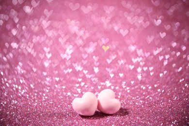 Photo of Romantic decor. Small hearts on shiny pink glitter and heart shaped lights, space for text. Bokeh effect