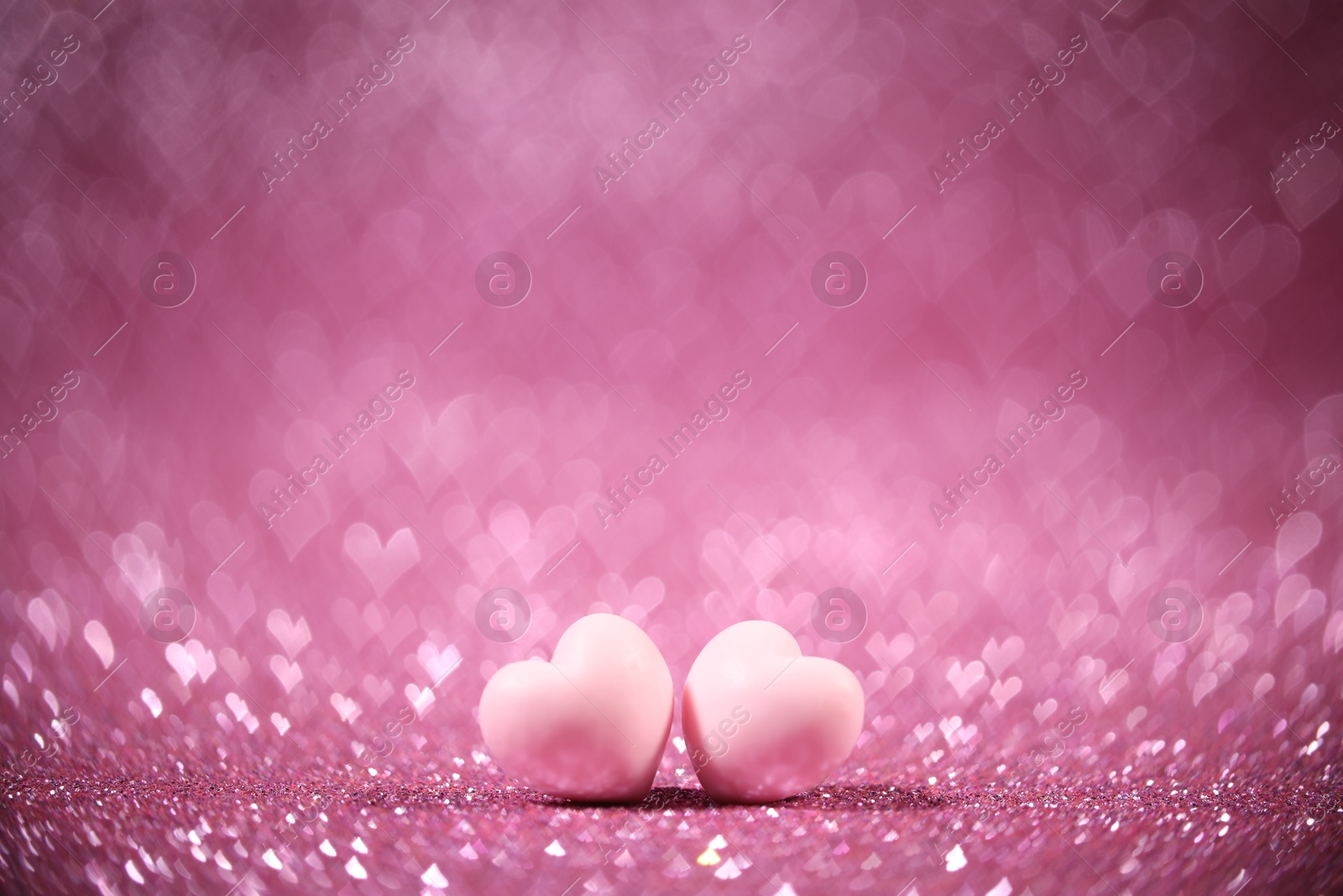 Photo of Romantic decor. Small hearts on shiny pink glitter and heart shaped lights, space for text. Bokeh effect