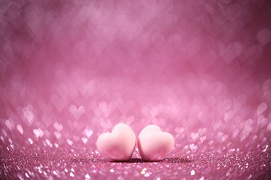 Photo of Romantic decor. Small hearts on shiny pink glitter and heart shaped lights, space for text. Bokeh effect