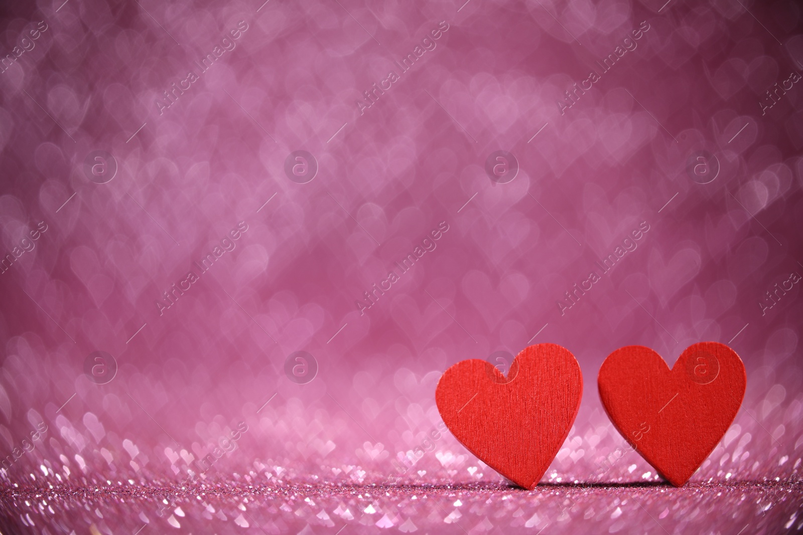 Photo of Romantic decor. Wooden hearts on shiny pink glitter and heart shaped lights, space for text. Bokeh effect