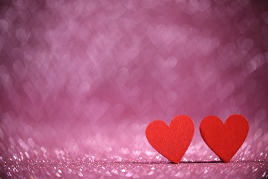 Photo of Romantic decor. Wooden hearts on shiny pink glitter and heart shaped lights, space for text. Bokeh effect