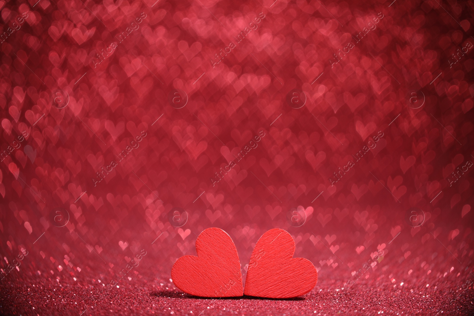 Photo of Romantic decor. Wooden hearts on shiny red glitter and heart shaped lights, space for text. Bokeh effect