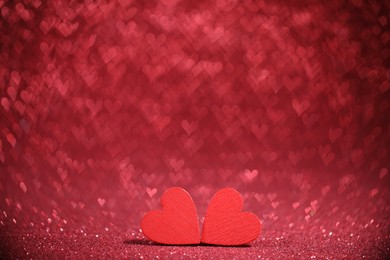 Photo of Romantic decor. Wooden hearts on shiny red glitter and heart shaped lights, space for text. Bokeh effect