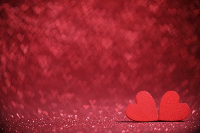 Photo of Romantic decor. Wooden hearts on shiny red glitter and heart shaped lights, space for text. Bokeh effect