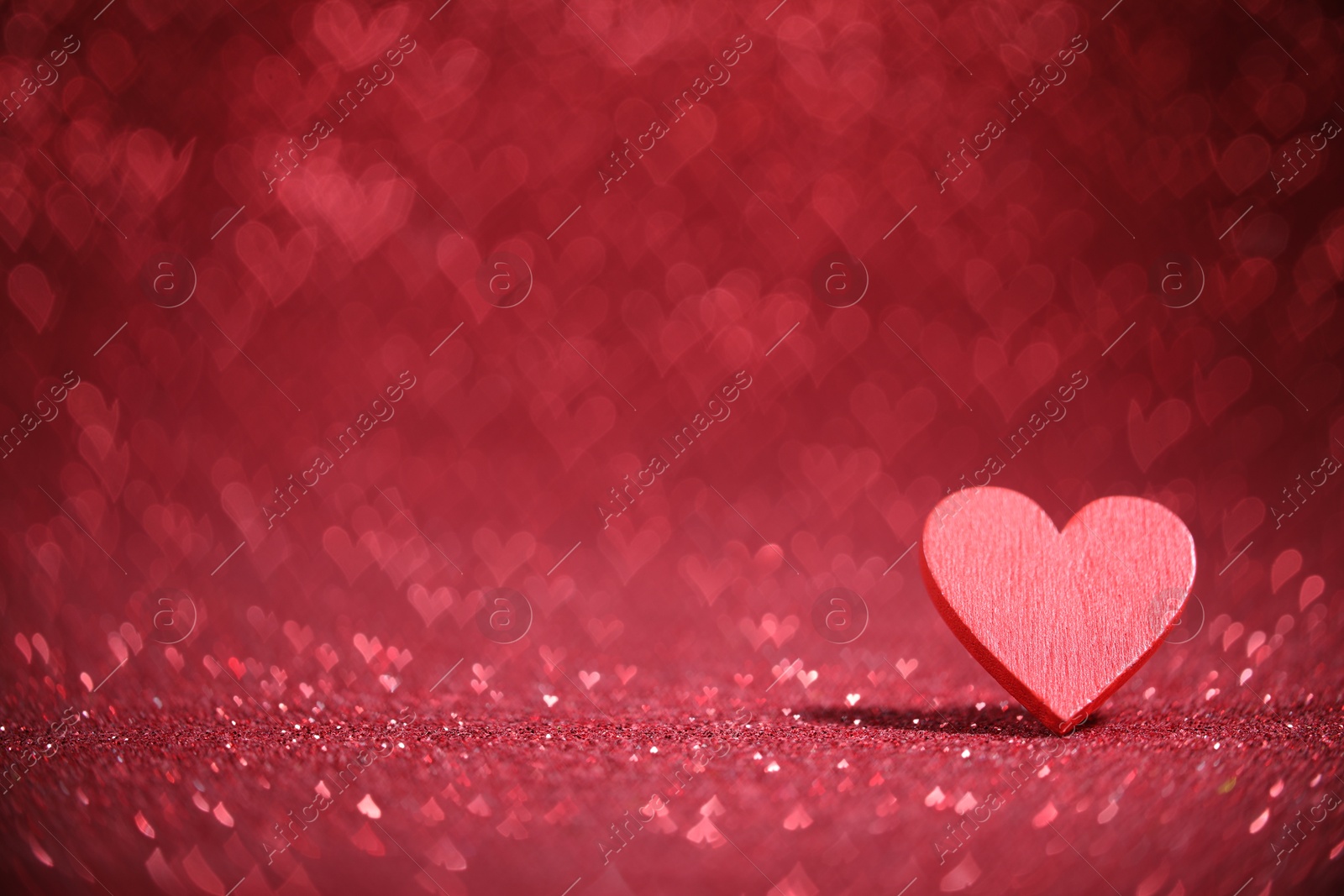 Photo of Romantic decor. Wooden heart on shiny red glitter and bokeh lights, space for text