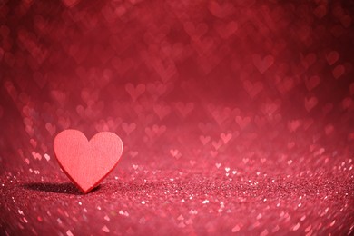 Photo of Romantic decor. Wooden heart on shiny red glitter and bokeh lights, space for text