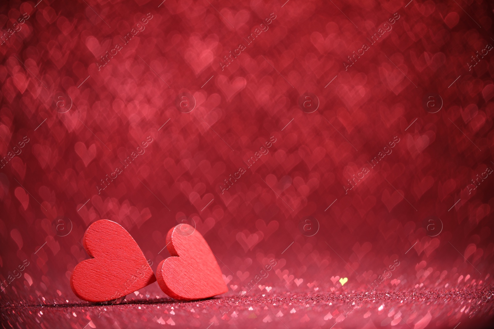 Photo of Romantic decor. Wooden hearts on shiny red glitter and heart shaped lights, space for text. Bokeh effect