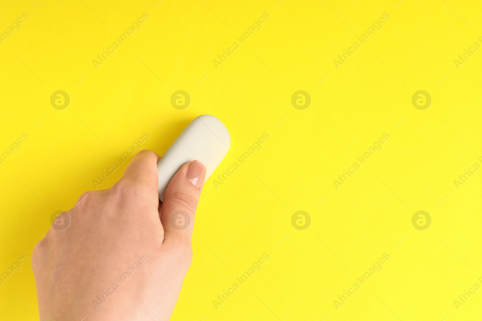 Photo of Woman using eraser on yellow background, closeup. Space for text