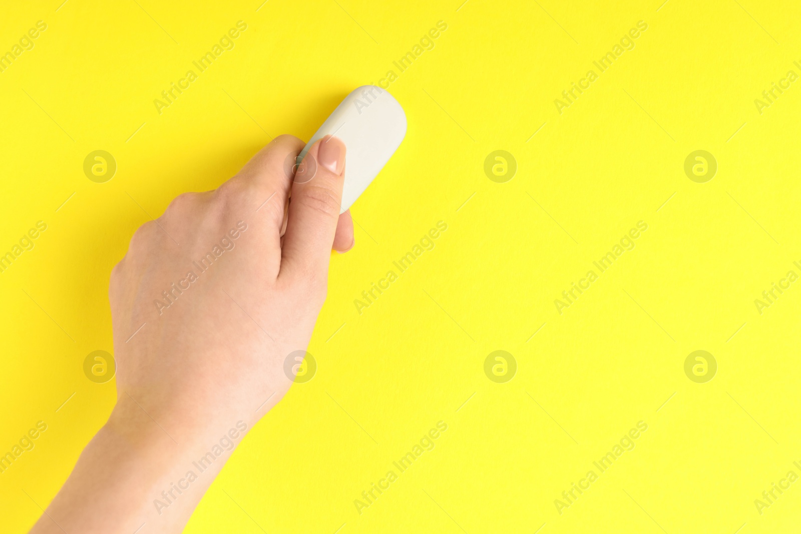 Photo of Woman using eraser on yellow background, closeup. Space for text