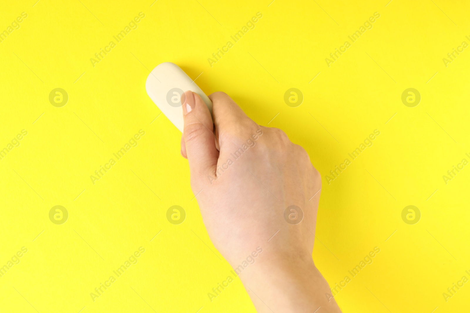 Photo of Woman using eraser on yellow background, closeup