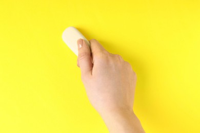 Photo of Woman using eraser on yellow background, closeup