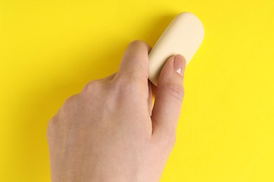 Photo of Woman using eraser on yellow background, closeup