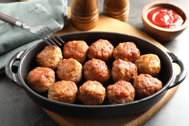 Photo of Tasty meatballs in baking dish served on grey table