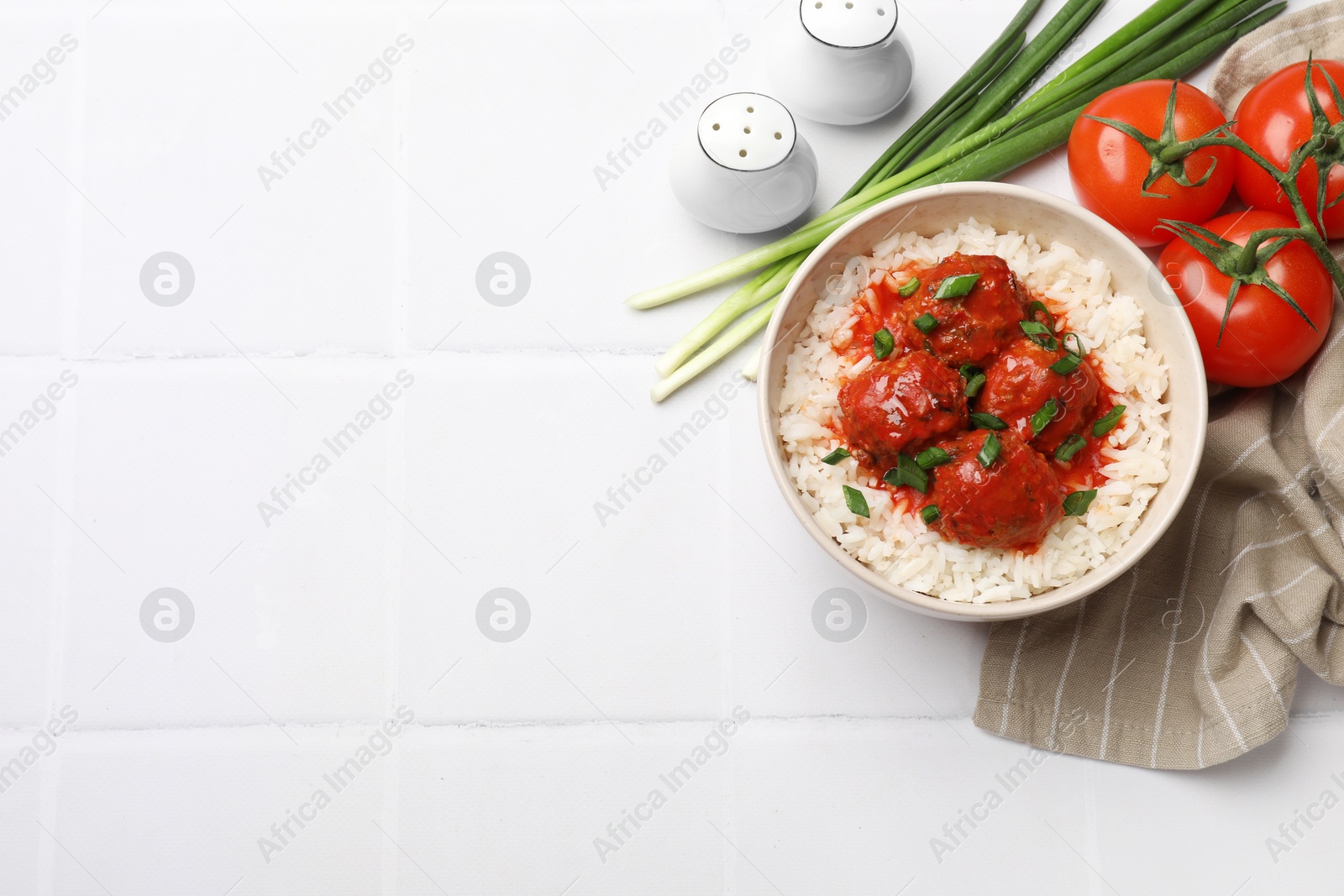 Photo of Tasty meatballs with sauce, rice and products on white tiled table, flat lay. Space for text