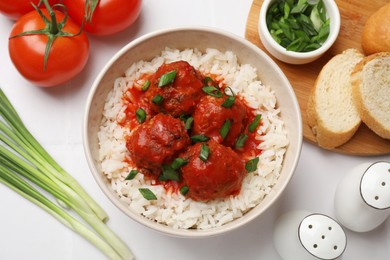 Photo of Tasty meatballs with sauce, rice and products on white tiled table, flat lay