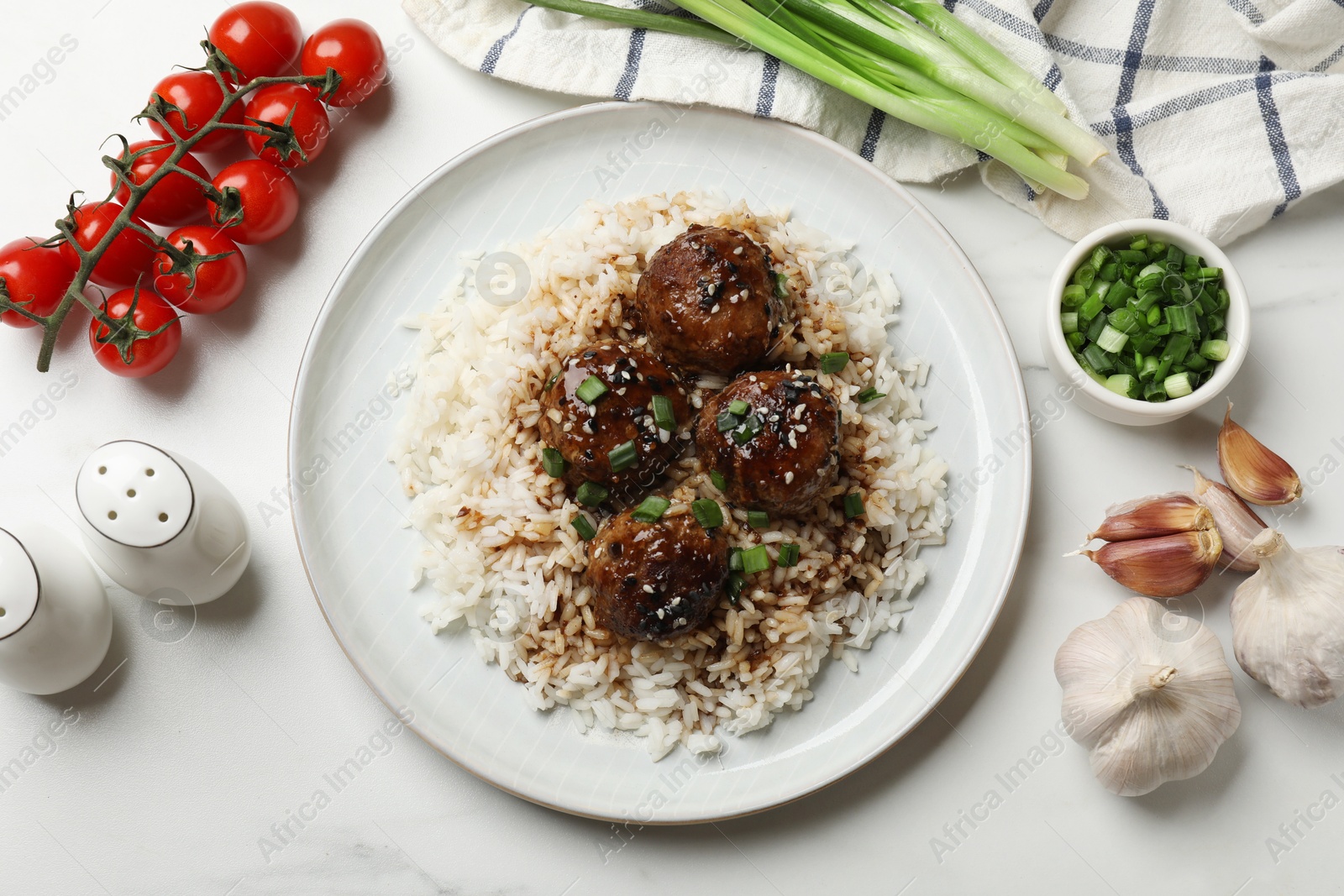 Photo of Delicious rice with meatballs, sauce and green onions on white table, flat lay