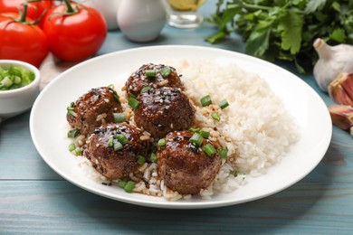 Photo of Delicious rice with meatballs, sauce and green onions on blue wooden table, closeup