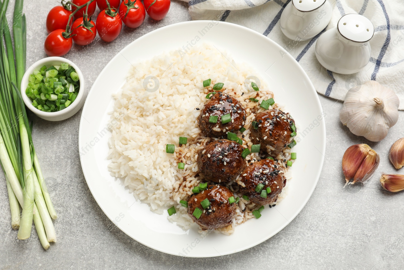 Photo of Delicious rice with meatballs, sauce and green onions on grey table, flat lay