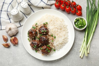 Photo of Delicious rice with meatballs, sauce and green onions on grey table, flat lay