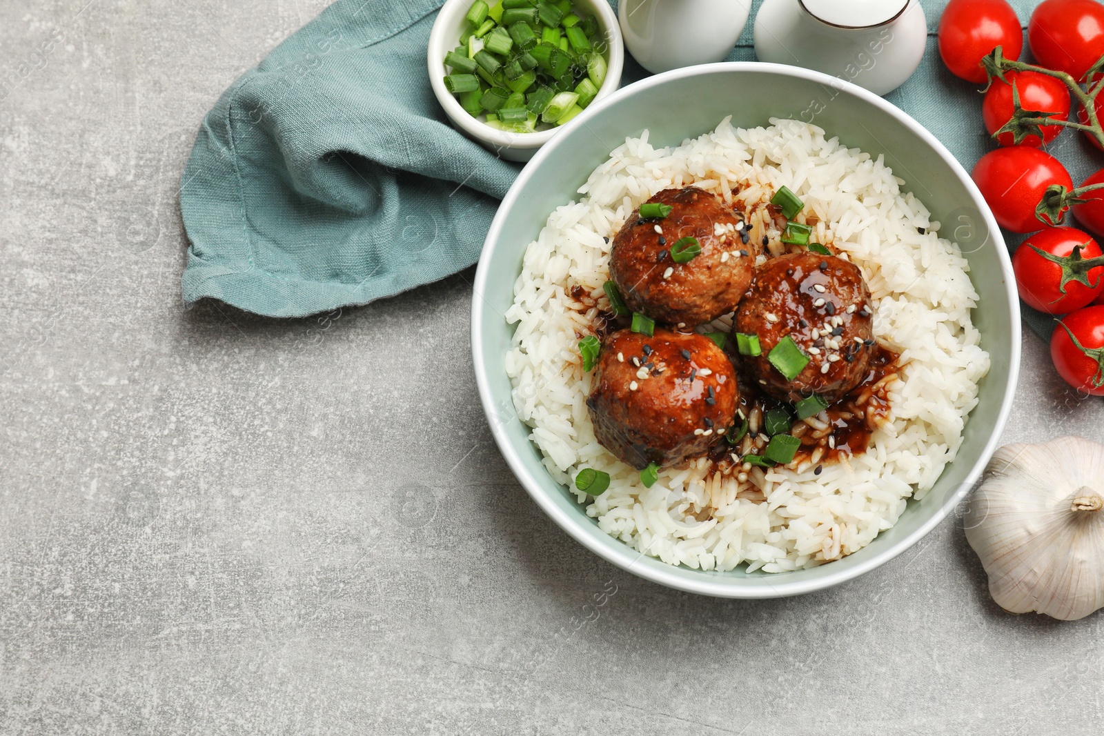 Photo of Delicious rice with meatballs, sauce and green onions on grey table, flat lay. Space for text