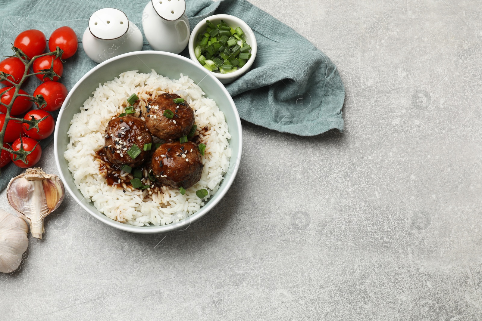 Photo of Delicious rice with meatballs, sauce and green onions on grey table, flat lay. Space for text