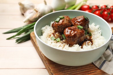 Photo of Delicious rice with meatballs, sauce and green onions on white wooden table, closeup