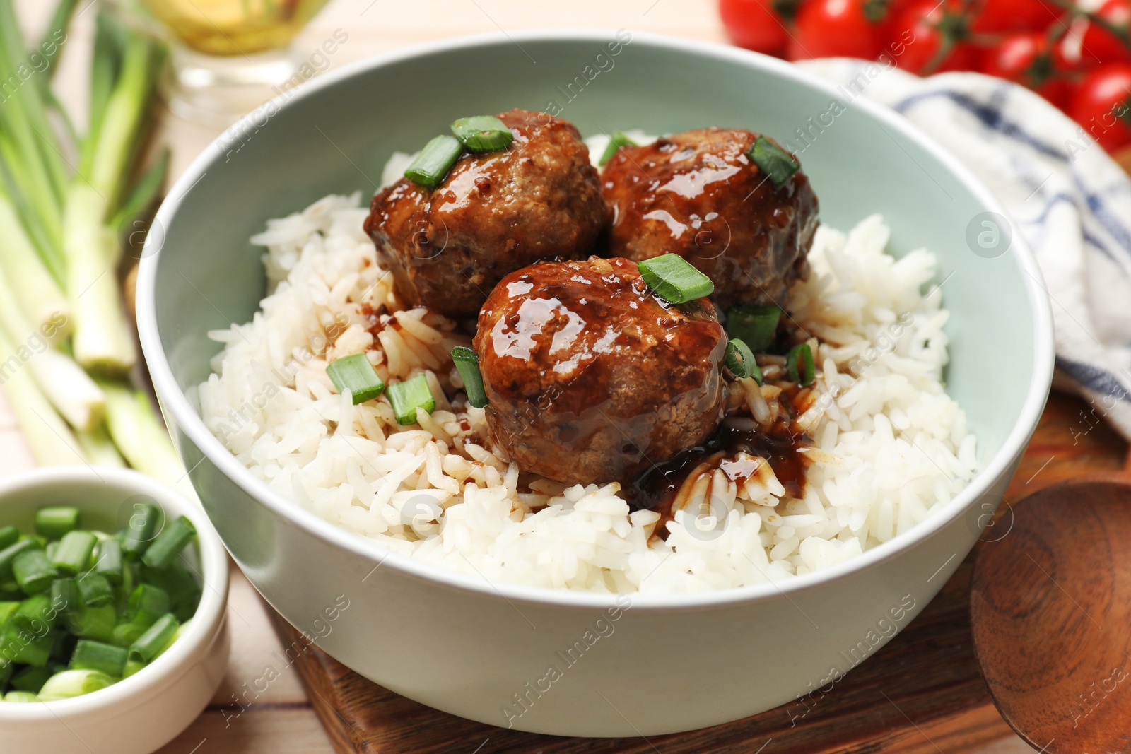 Photo of Delicious rice with meatballs, sauce and green onions on white wooden table, closeup