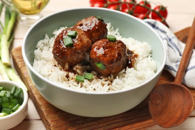 Photo of Delicious rice with meatballs, sauce and green onions on white wooden table, closeup