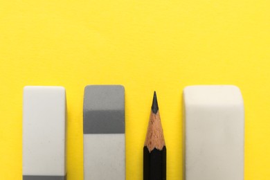 Photo of Erasers and pencil on yellow background, flat lay. Space for text