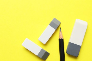 Photo of Erasers and pencil on yellow background, flat lay. Space for text