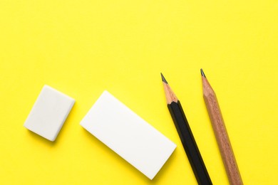 Photo of Erasers and pencils on yellow background, flat lay. Space for text