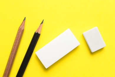 Photo of Erasers and pencils on yellow background, flat lay