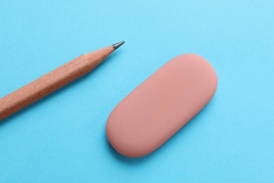 Photo of Eraser and pencil on light blue background, top view