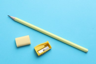 Photo of Eraser, pencil and sharpener on light blue background, top view. Space for text