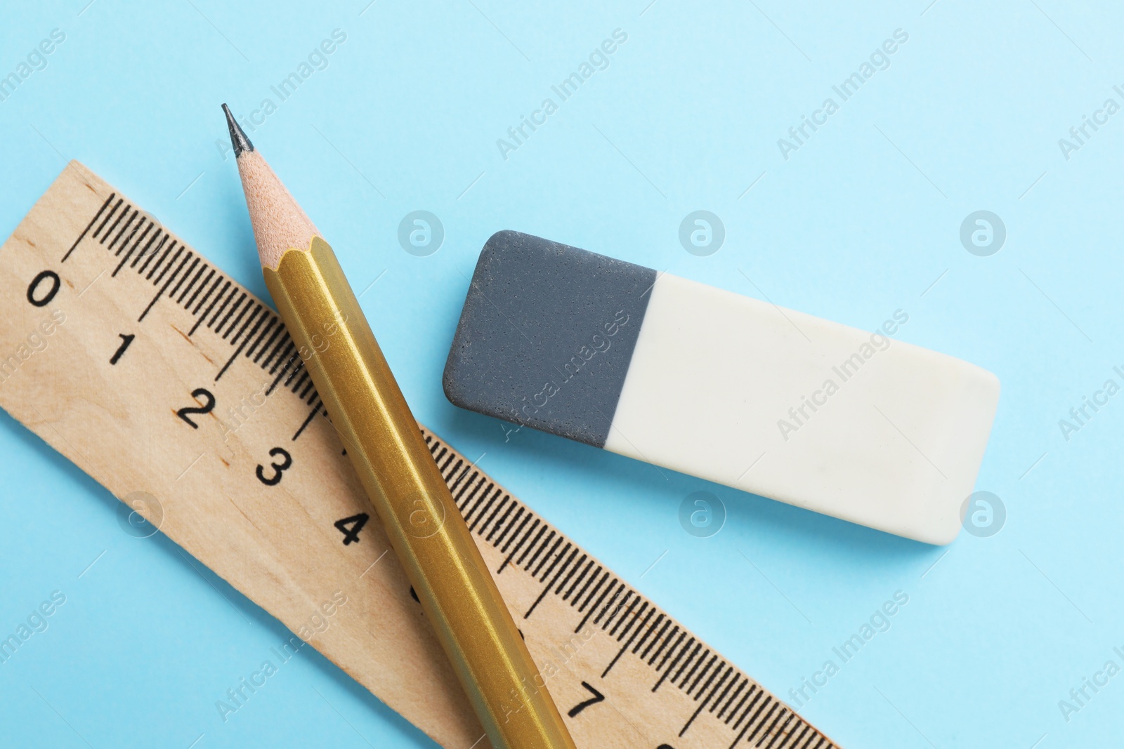 Photo of Eraser, pencil and ruler on light blue background, top view