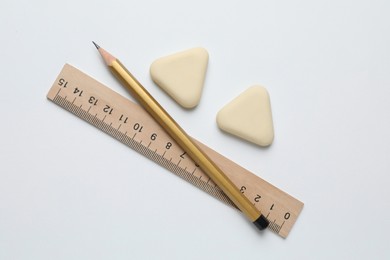 Photo of Erasers, ruler and pencil on white background, flat lay