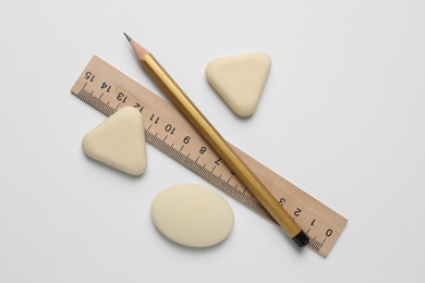 Photo of Erasers, ruler and pencil on white background, flat lay