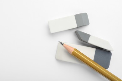 Photo of Erasers and pencil on white background, flat lay. Space for text