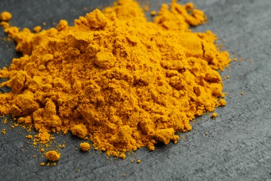 Photo of Heap of turmeric powder on grey table, closeup