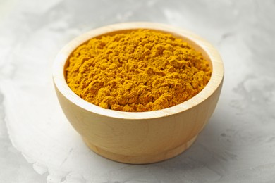 Photo of Turmeric powder in bowl on light table, closeup