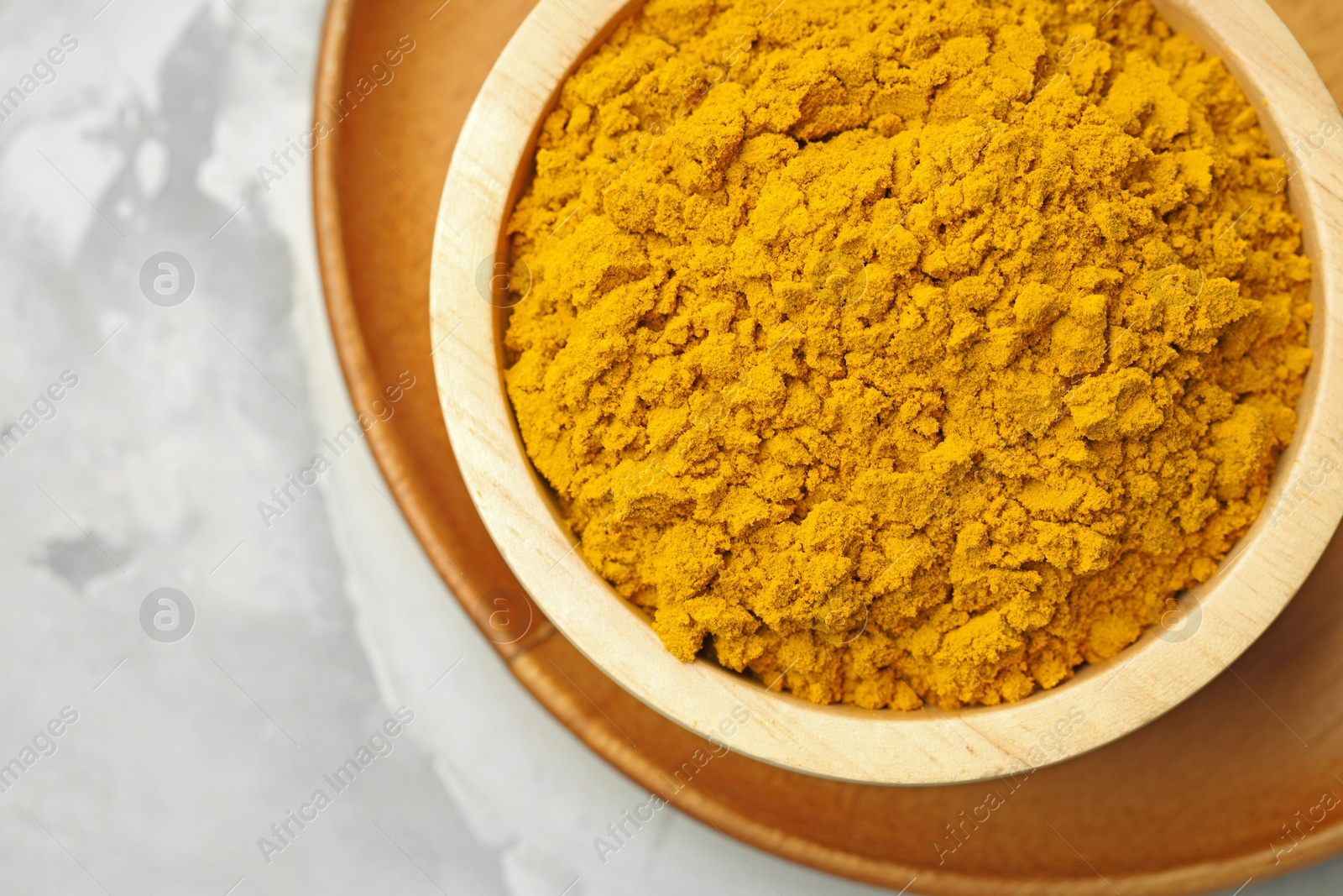 Turmeric powder in bowl on light grey table, top view Photo of Turmeric powder in bowl on light grey table, top view