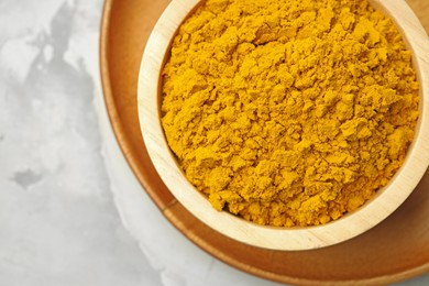 Photo of Turmeric powder in bowl on light grey table, top view