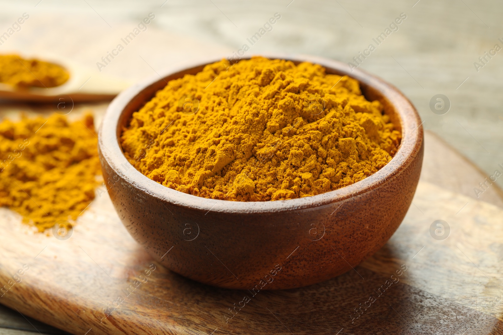 Photo of Turmeric powder in bowl on table, closeup