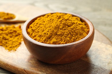 Photo of Turmeric powder in bowl on table, closeup