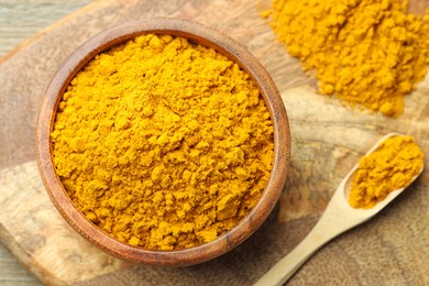 Photo of Turmeric powder in bowl and spoon on table, top view